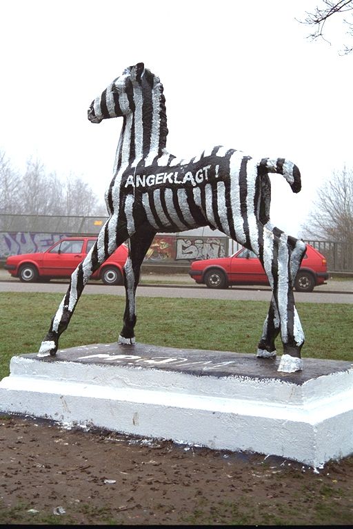 Holbein-Pferd schwarz-weiß gestreift in Sträflingskleidung mit Aufschrift „Angeklagt“, 1997
